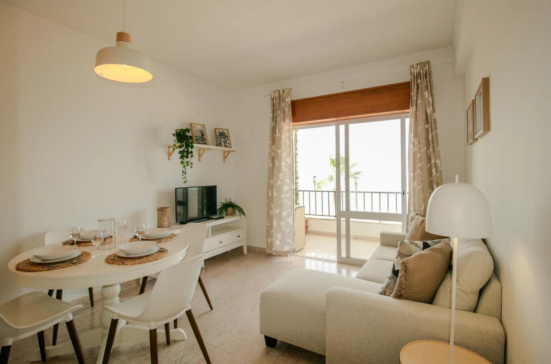 A bright living and dining area opens onto a balcony through sliding glass doors.