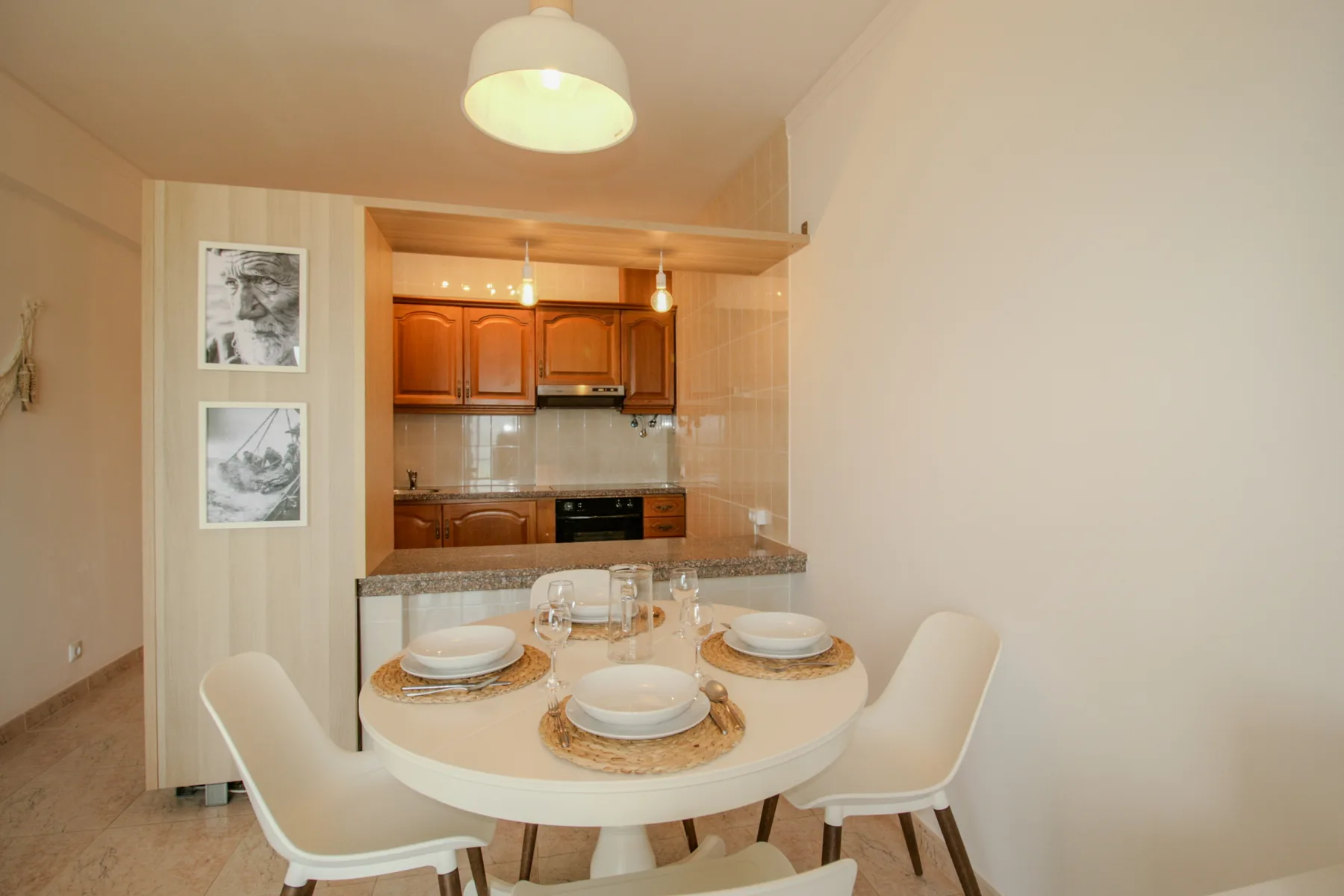 A dining area with a round table set in front of an open kitchen.