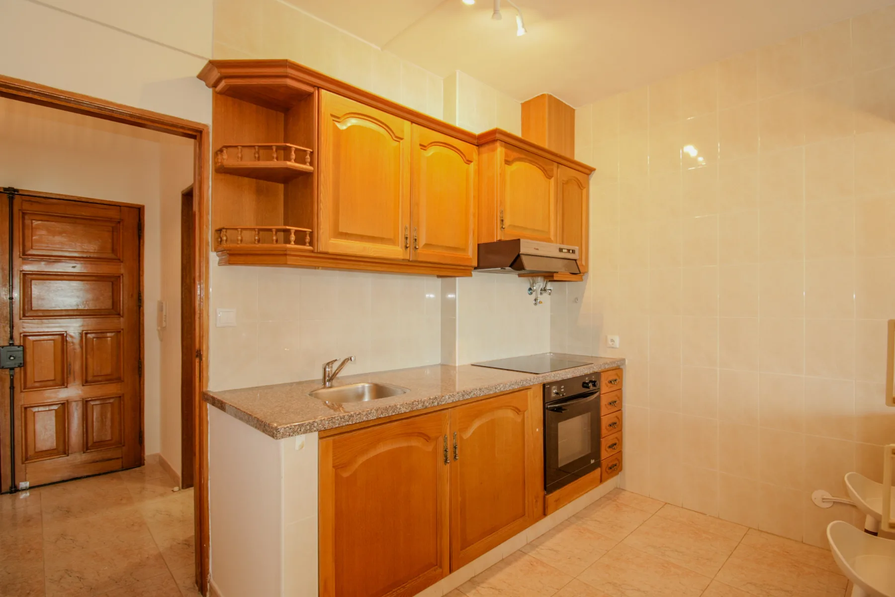 A kitchen with wooden cabinets, a countertop, and a built-in oven.