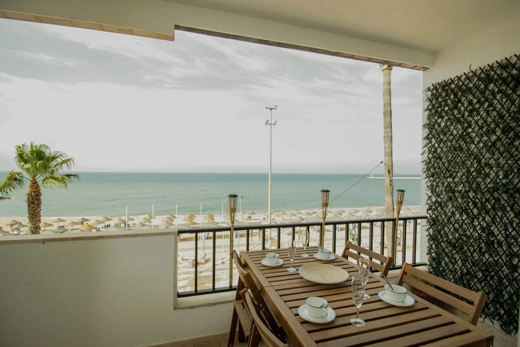 A seaside dining terrace with a wooden table overlooking the water.