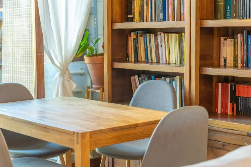 Un comedor con una mesa de madera, asientos y estanterías.