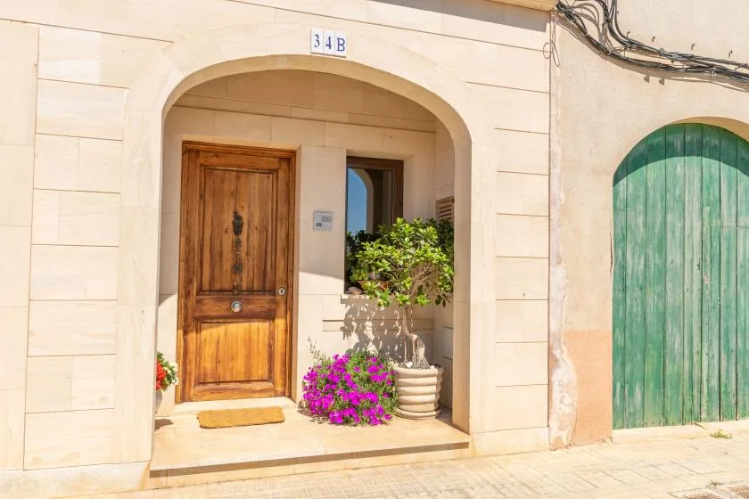 Una entrada de edificio con arco, puerta de madera y flores en macetas.