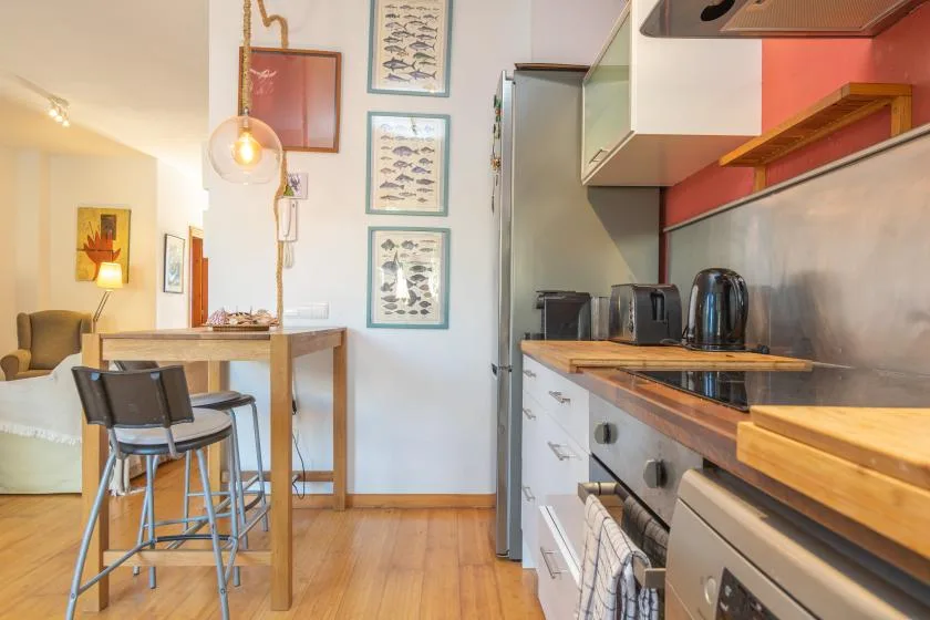 Una cocina compacta con una encimera de madera se abre a un comedor.
