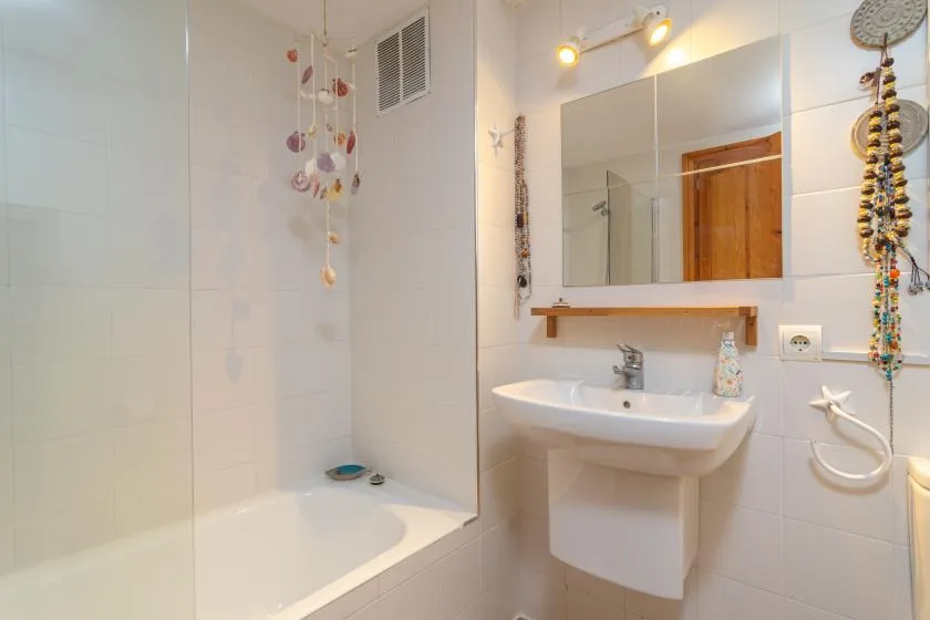 Un baño alicatado con bañera, lavabo y espejo de pared.