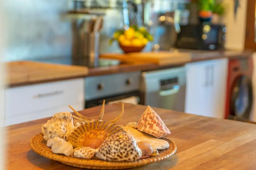 Una cocina con encimeras de madera y un cuenco de conchas marinas sobre la isla.