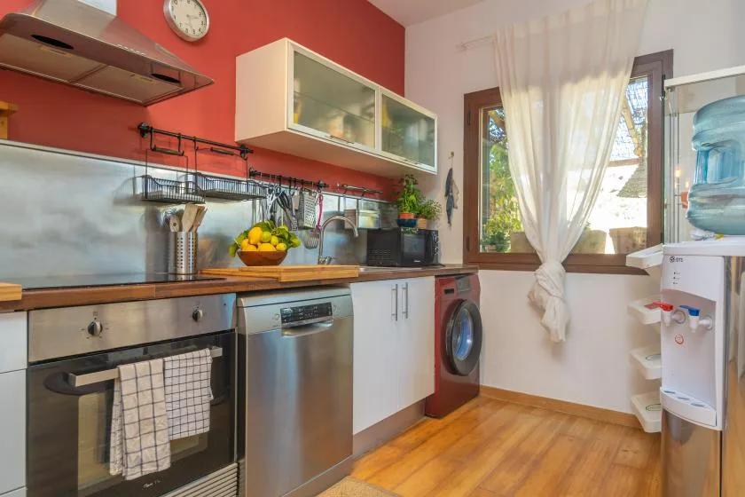 Una cocina con electrodomésticos de acero inoxidable y una ventana con vistas a la vegetación.