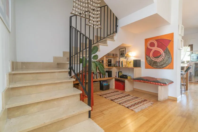 Una luminosa sala de estar cuenta con una escalera, estanterías y un banco integrado.
