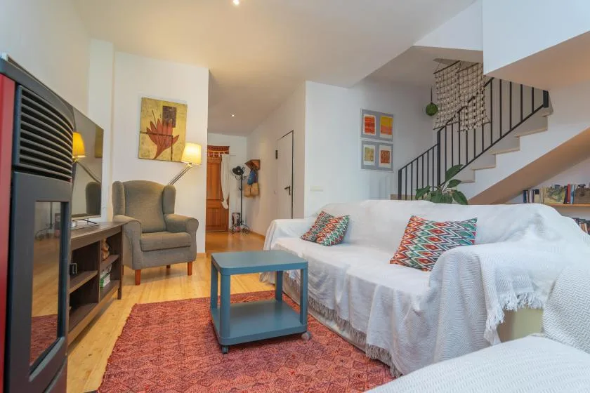 Una sala de estar con un sofá blanco, un sillón y una mesa de centro.