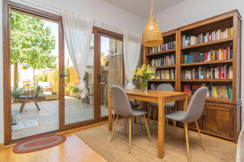 Comedor con una mesa de madera, sillas y una gran estantería.