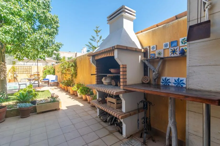 Un patio exterior cuenta con una barbacoa de obra y una encimera de azulejos.