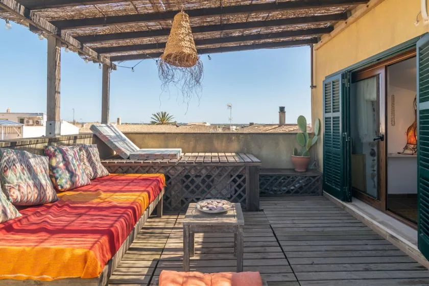 Una terraza en la azotea con asientos coloridos bajo una pérgola de madera.