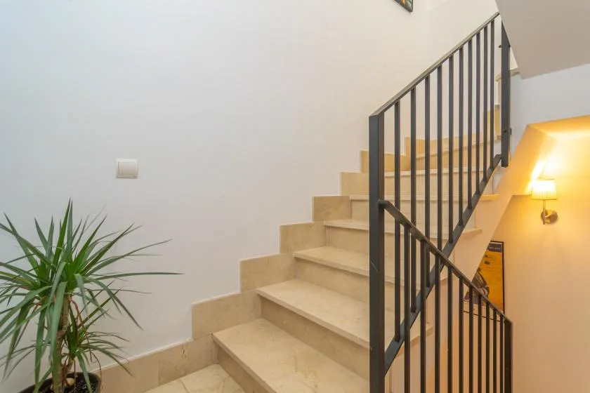 Una escalera con peldaños beige y una barandilla metálica oscura.