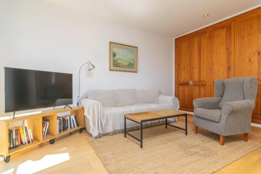 Una sala de estar con televisor, sofá, sillón y mesa de centro.