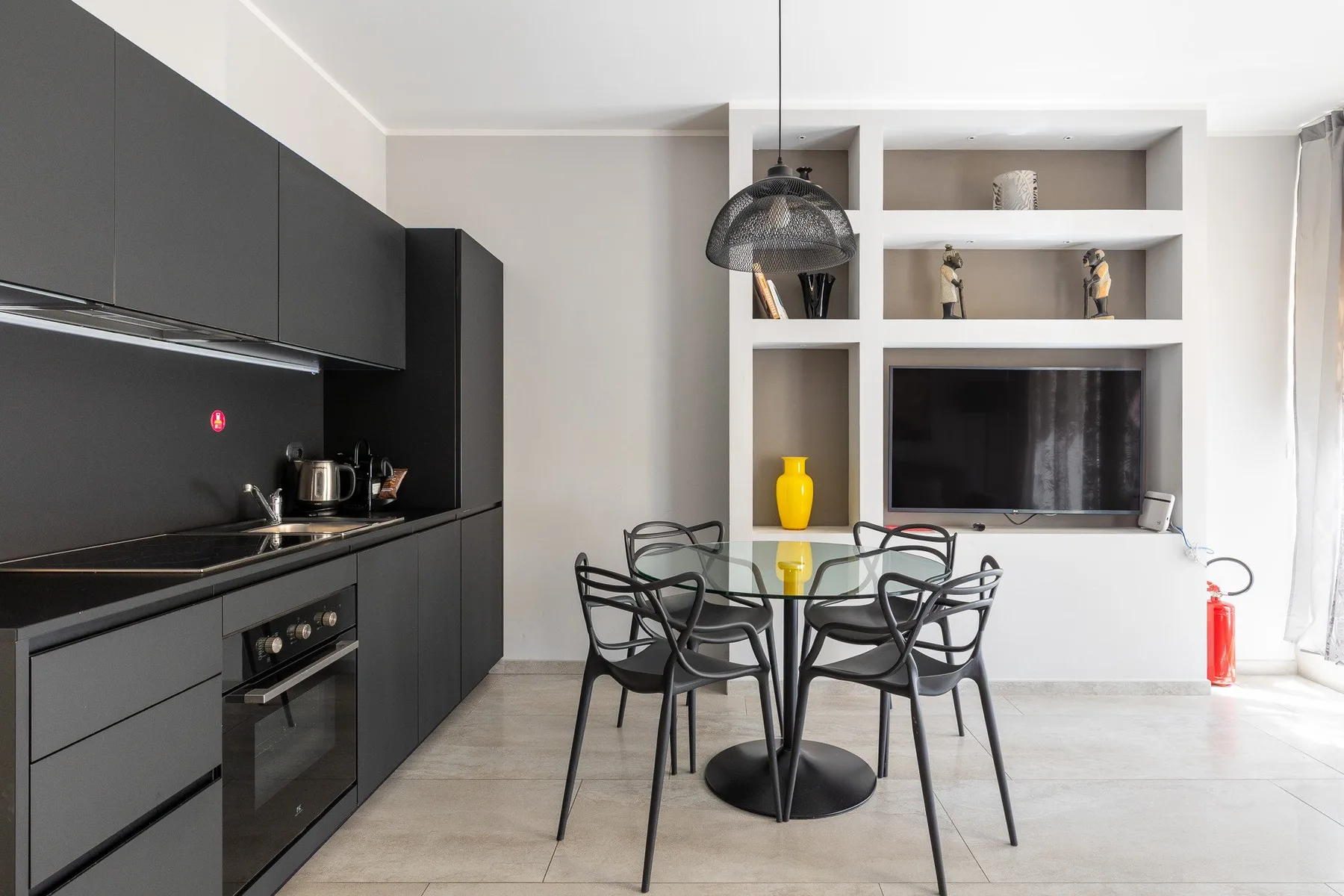 Una cocina moderna y zona de comedor con armarios oscuros y una mesa redonda.