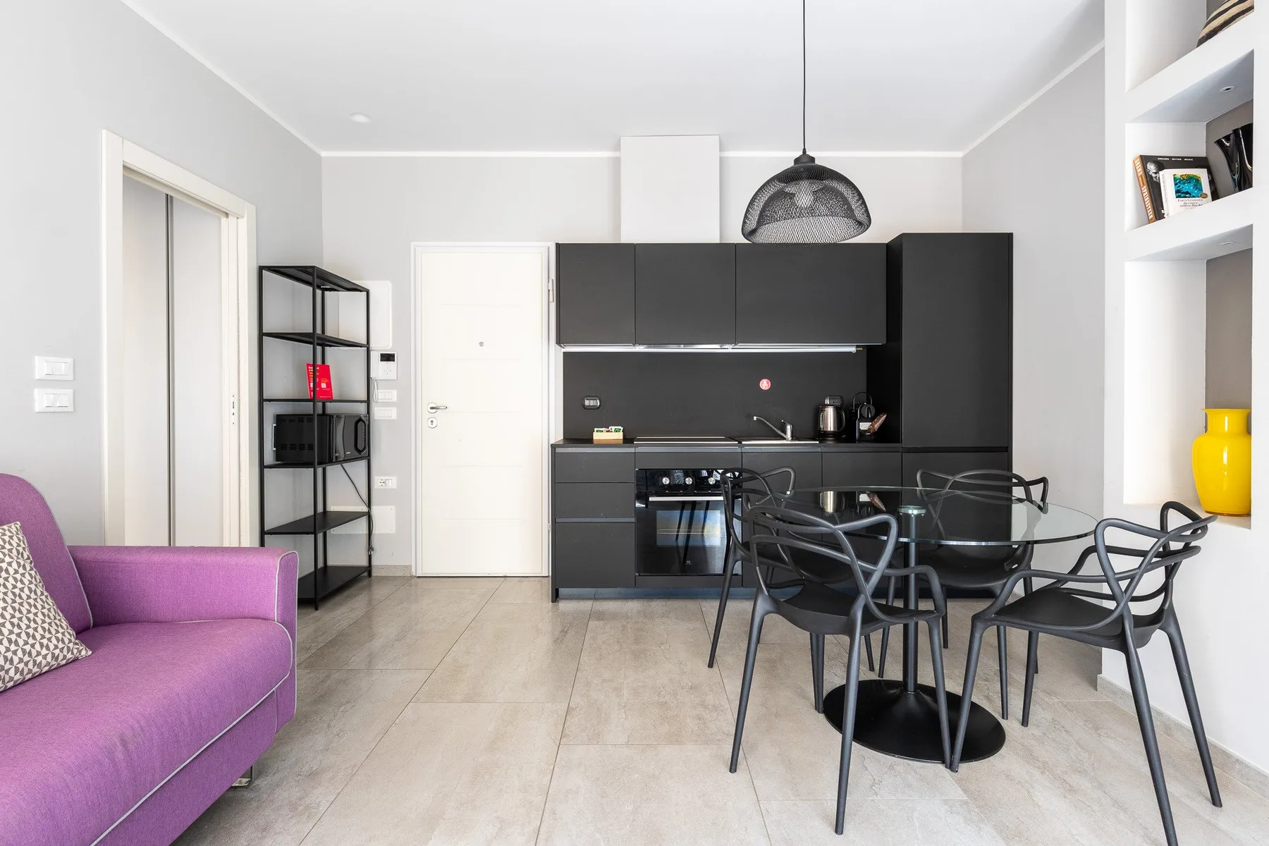 Una cocina moderna y zona de comedor con muebles oscuros y una mesa.