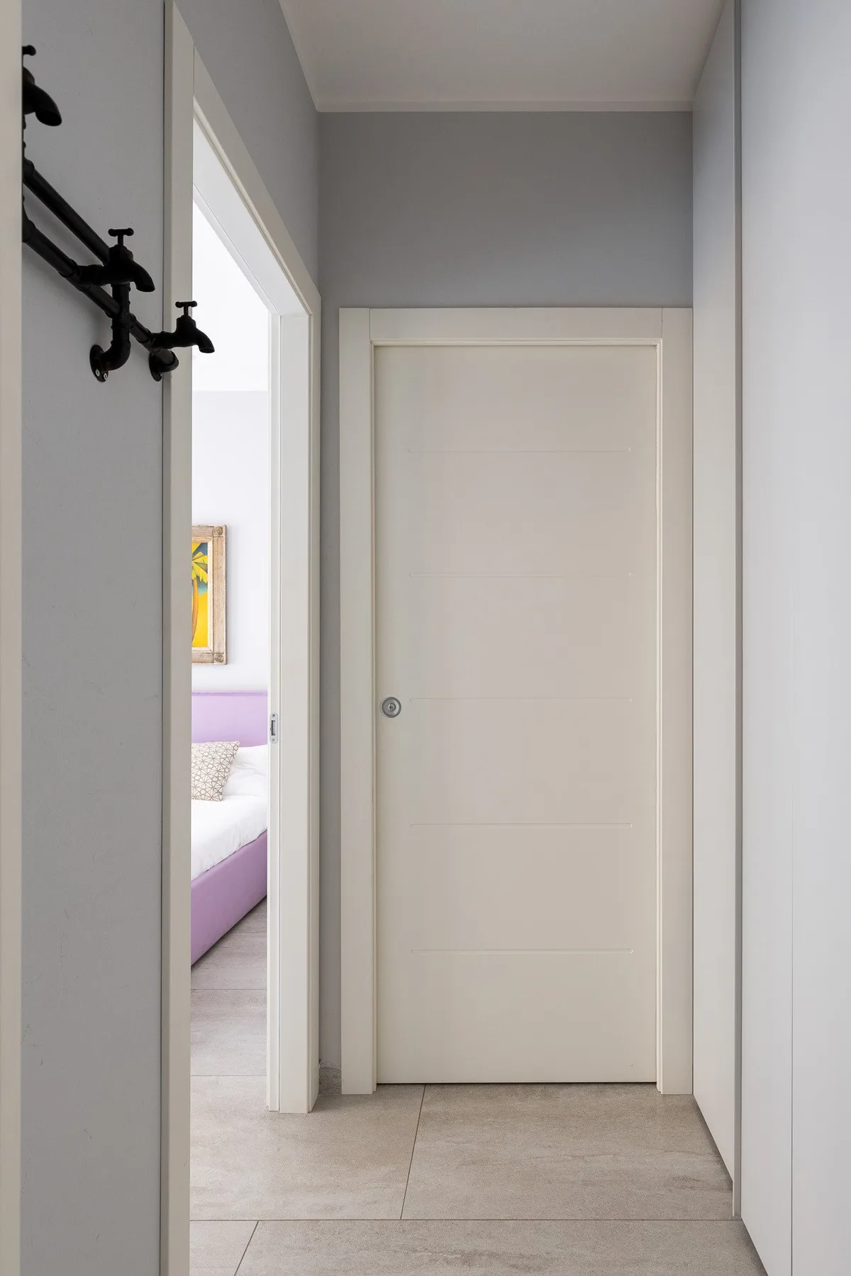 Un pasillo con una puerta cerrada y una entrada abierta a un dormitorio.