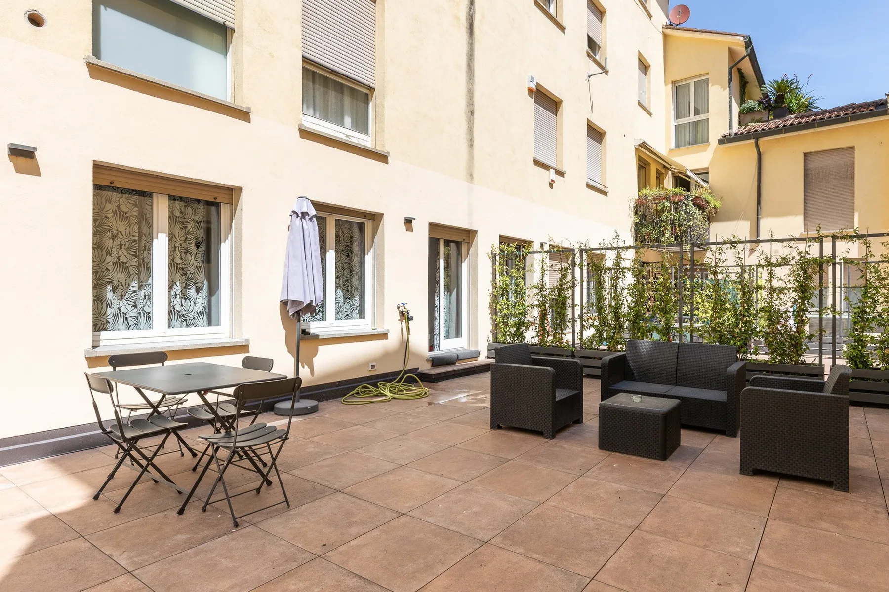 Una terraza soleada con asientos al aire libre junto a un edificio claro.
