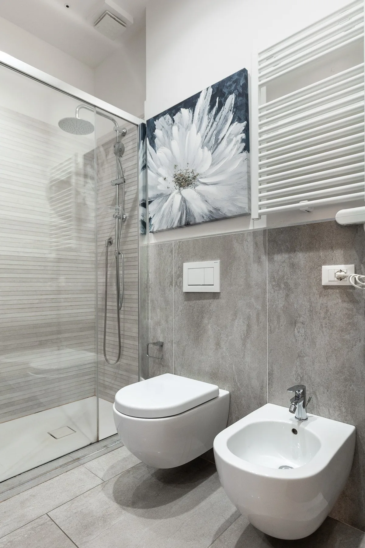 Un baño moderno con ducha de vidrio, inodoro suspendido y bidé.