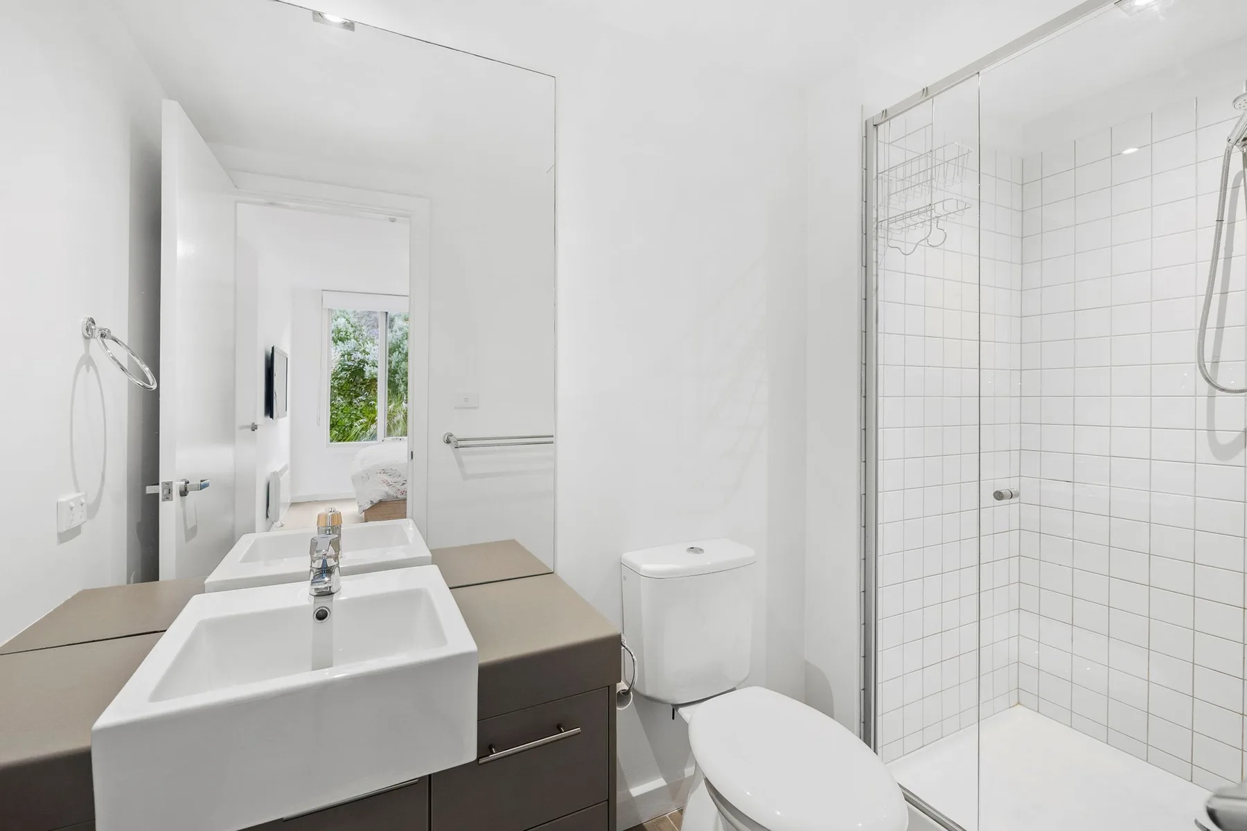A bright bathroom with a sink, toilet, and glass-enclosed shower.