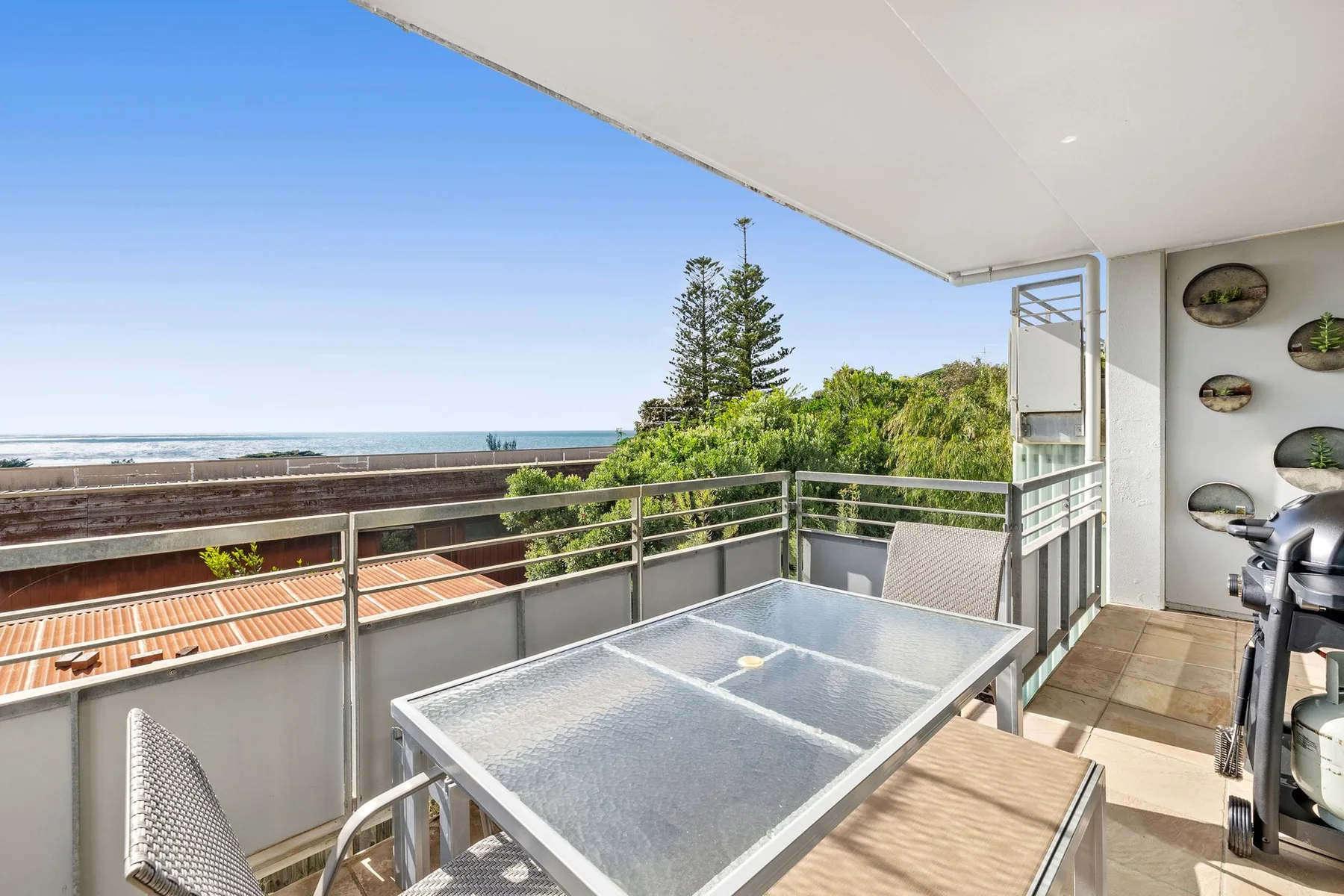 A balcony dining area overlooks the ocean and nearby rooftops.