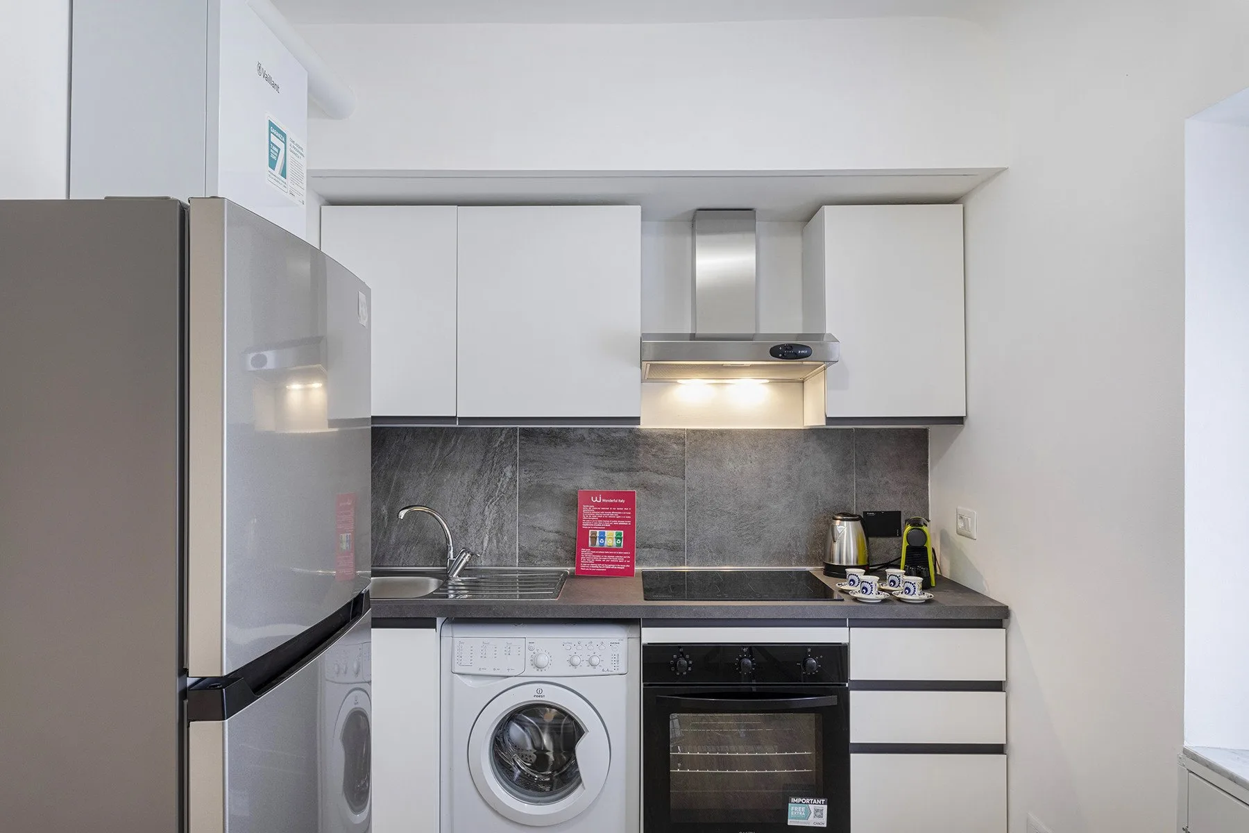 A compact kitchen with white cabinets, a washing machine, and an oven.
