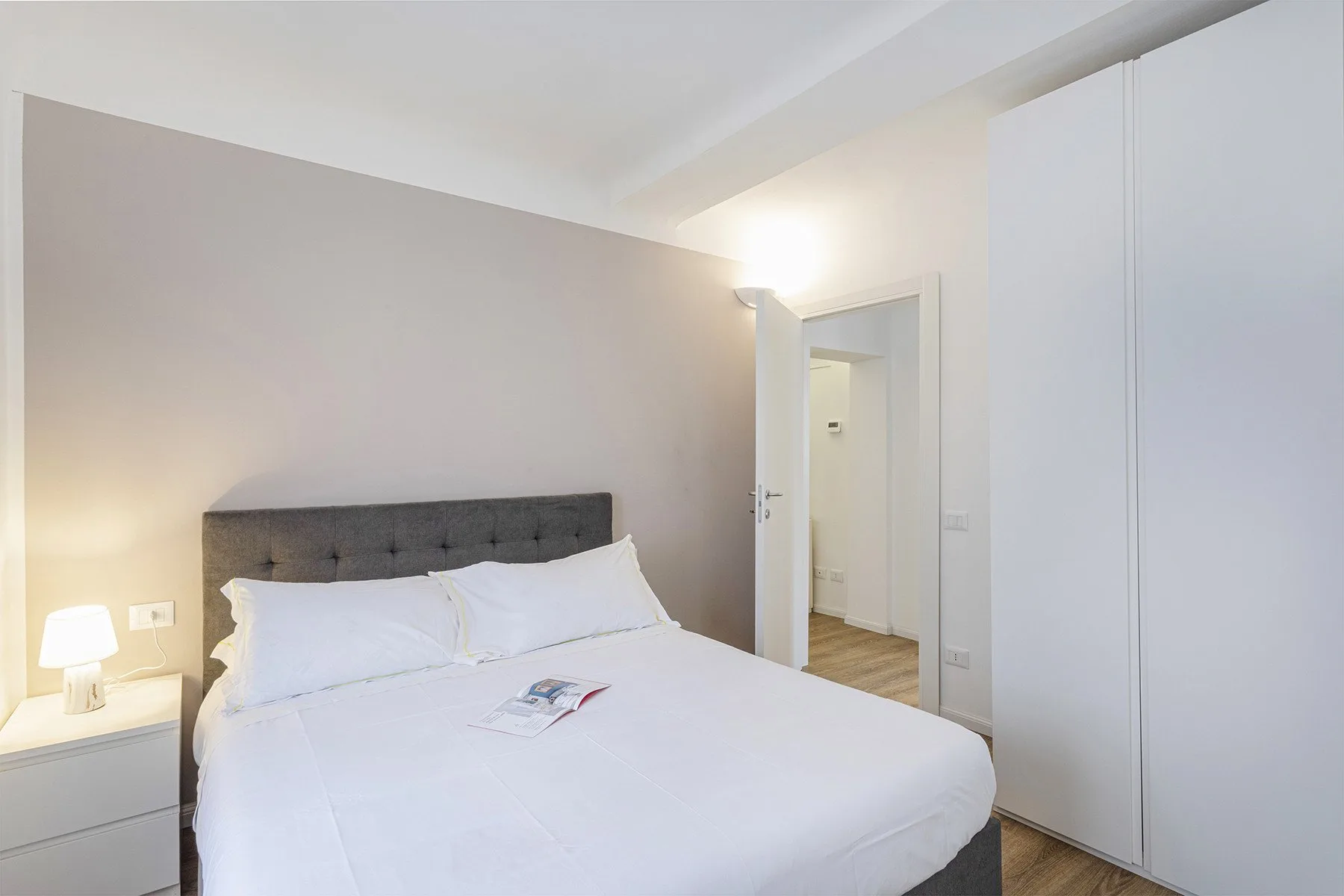 Un dormitorio luminoso con una cama bien hecha y un armario blanco.