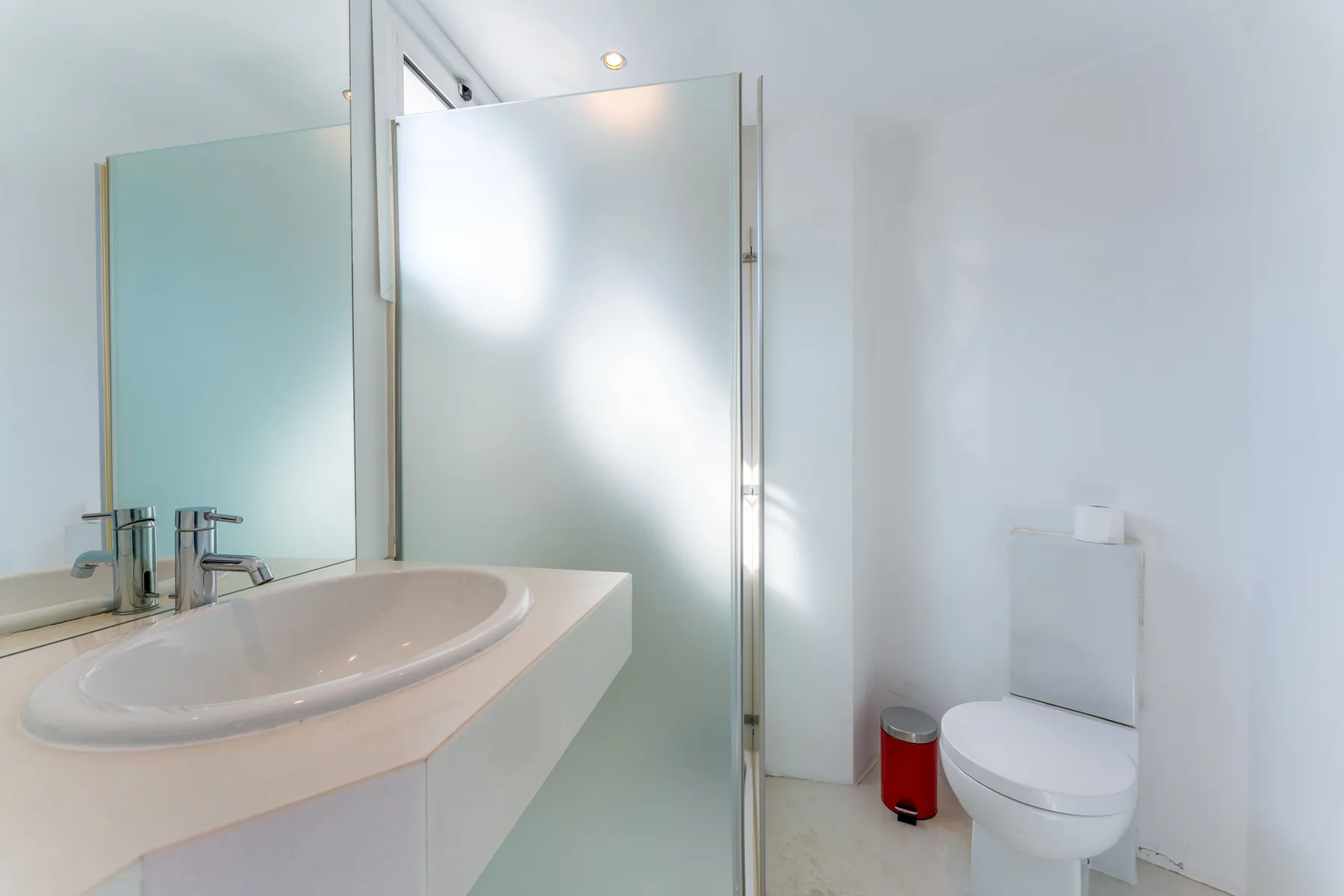 A bright bathroom with a sink, shower, and toilet.