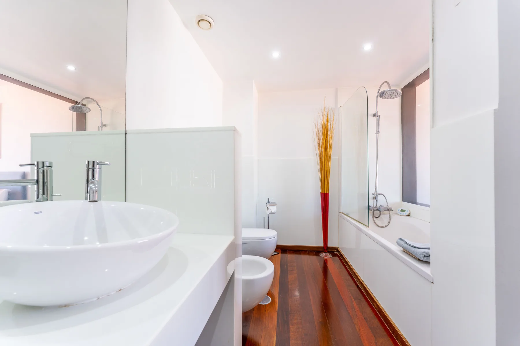 A bright bathroom with a sink, toilet, and bathtub along the wall.
