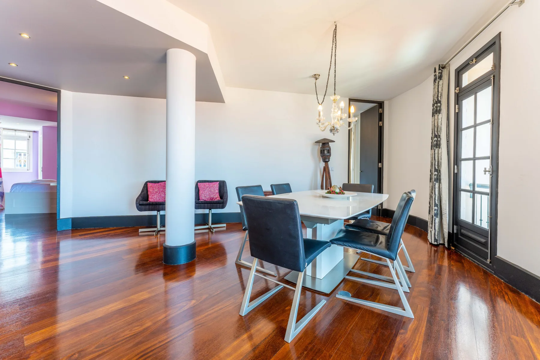 A dining area with a table and seating beside tall windows.