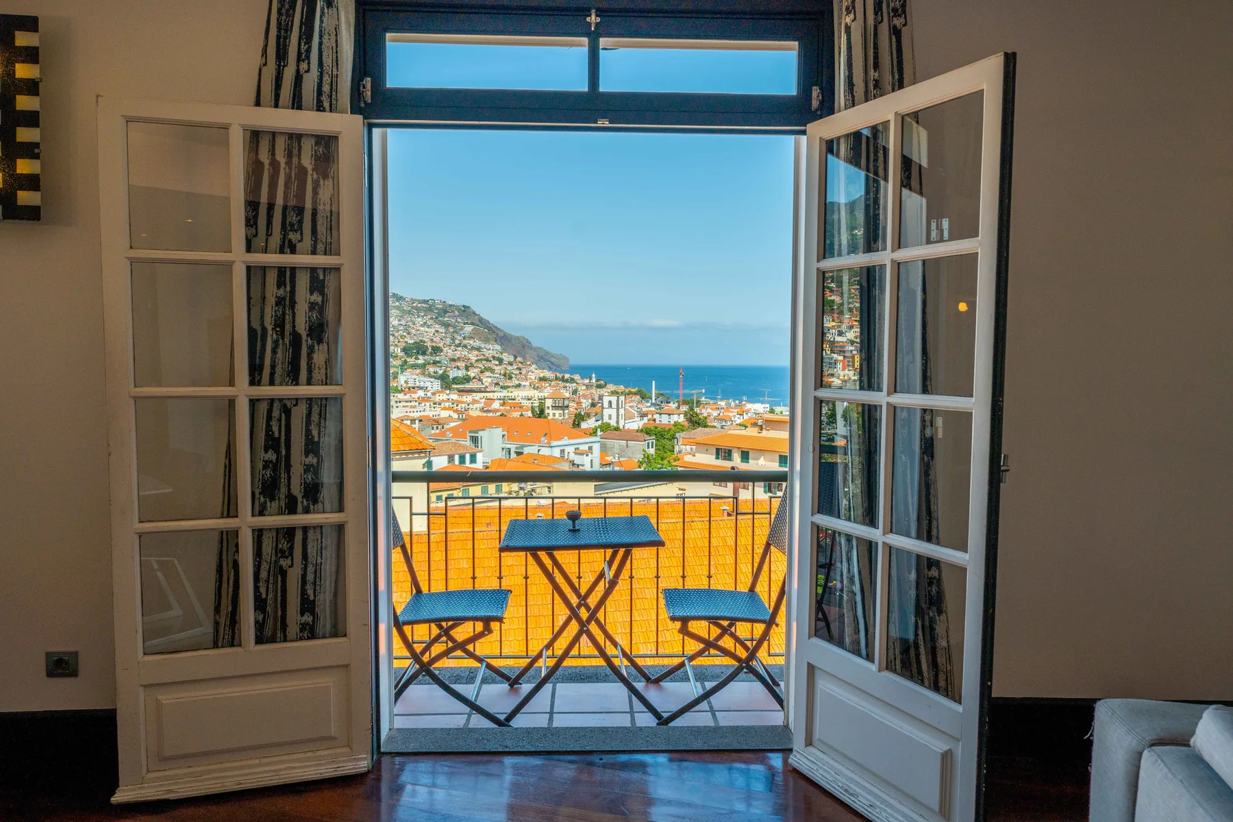 Las puertas abiertas dan a un balcón con asientos y vistas de la costa.