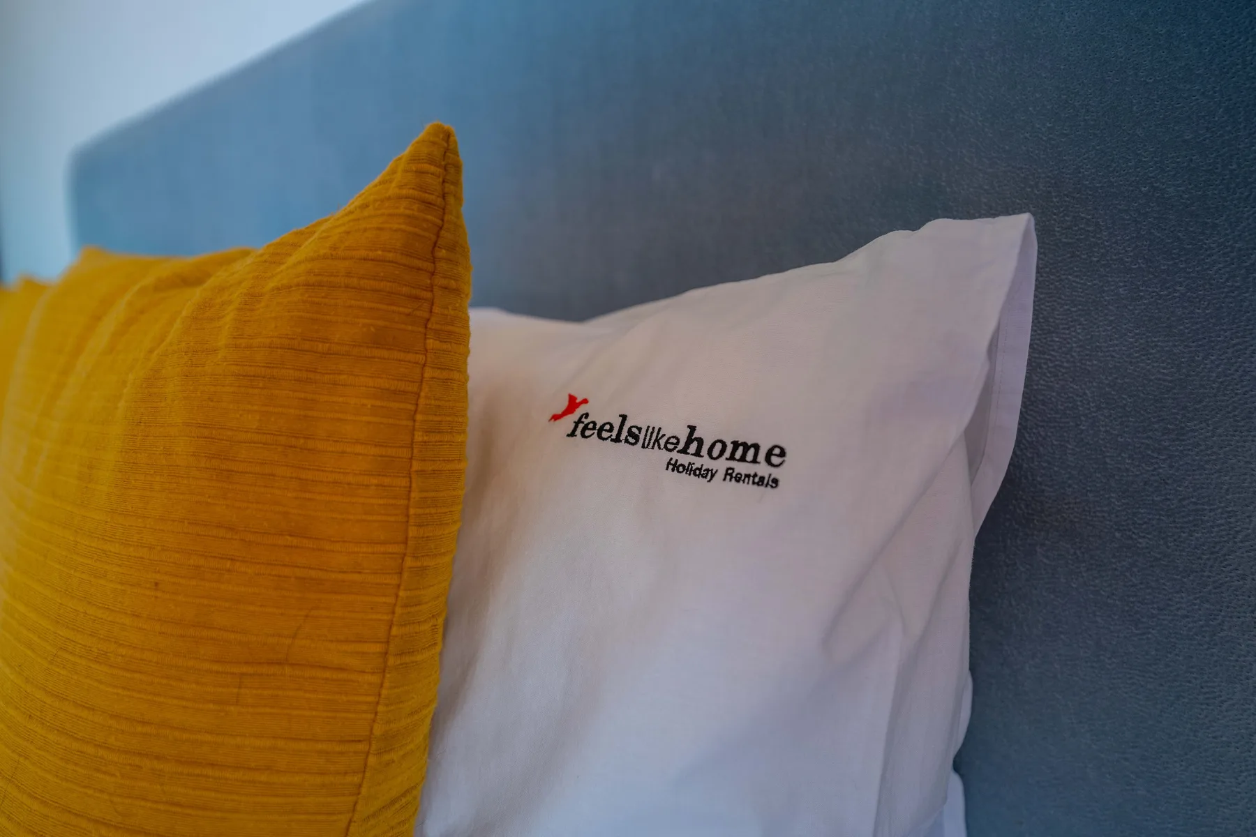 Bedroom pillows include a mustard-yellow cushion beside a white pillow.