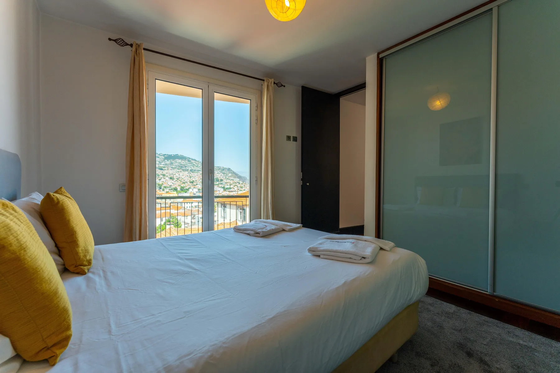 A bedroom with a bed beside glass doors opening onto a balcony.