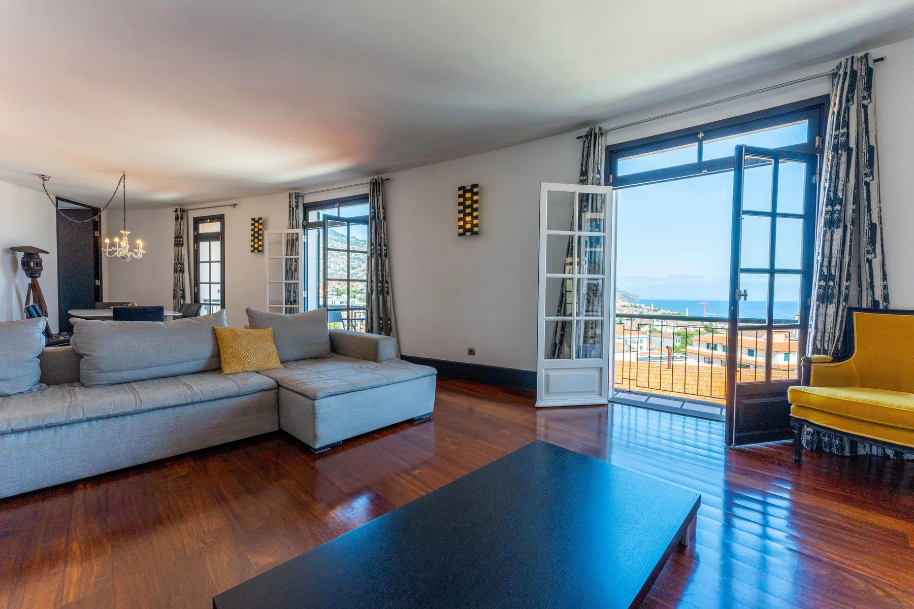 A living room with seating and large windows opening onto a balcony.