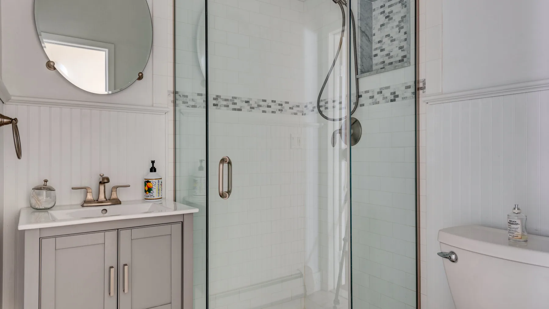 A bathroom with a glass shower, sink, and toilet.