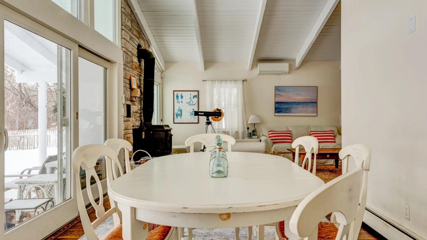 A bright dining area with a large oval table and glass doors overlooking a snowy yard.