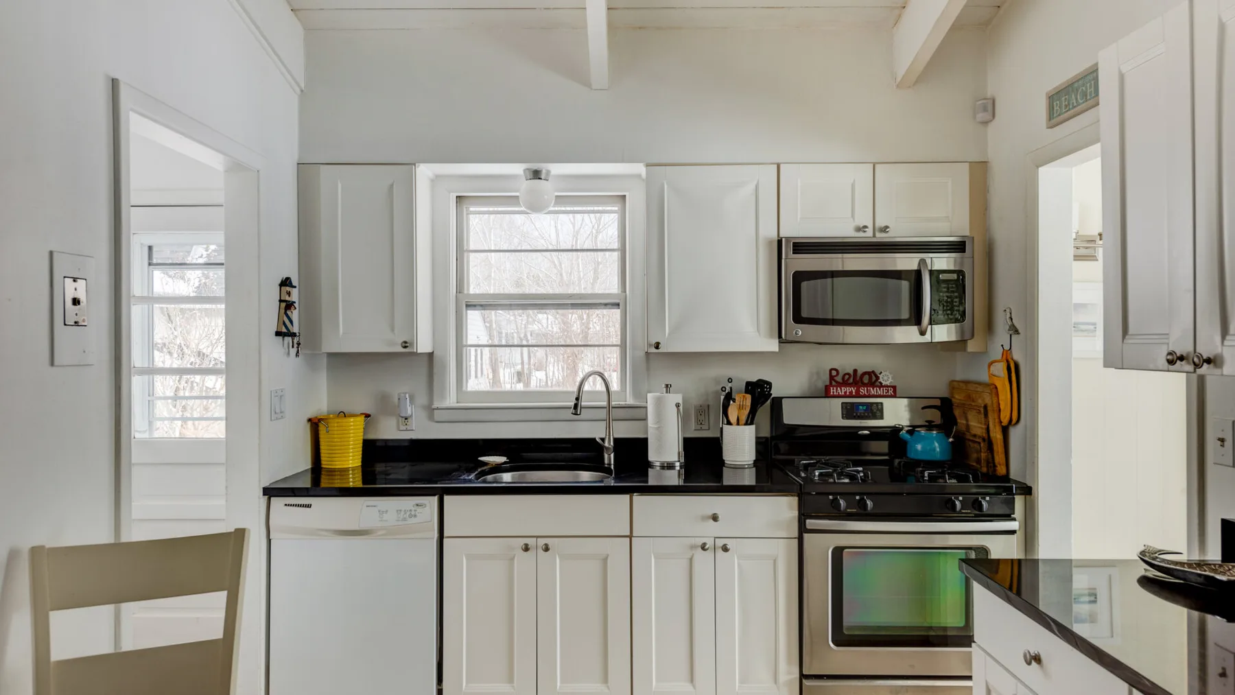 A bright kitchen with white cabinets, a window, and a stove.