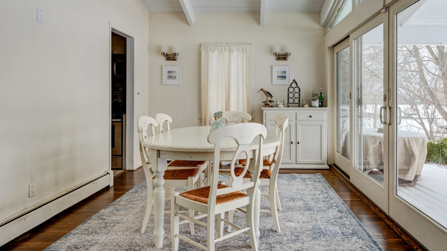 A bright dining area with a white table and large glass doors.