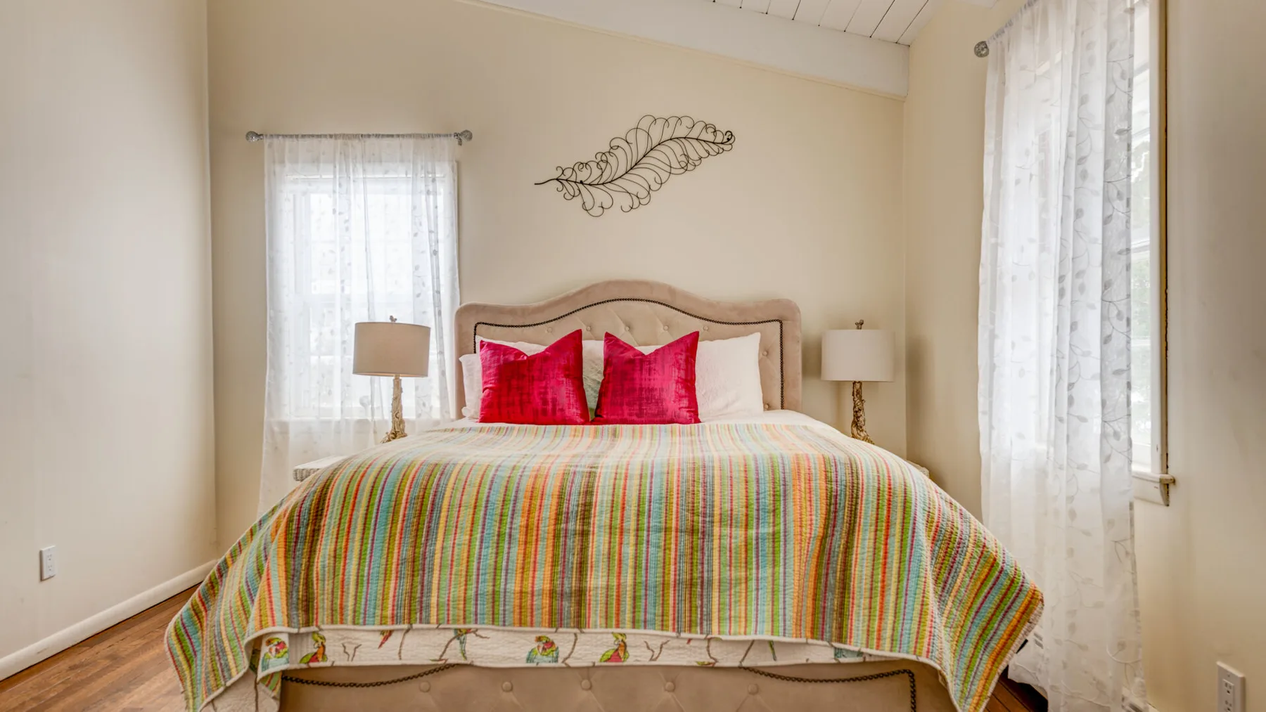 A bedroom with a large bed covered by a colorful striped blanket.