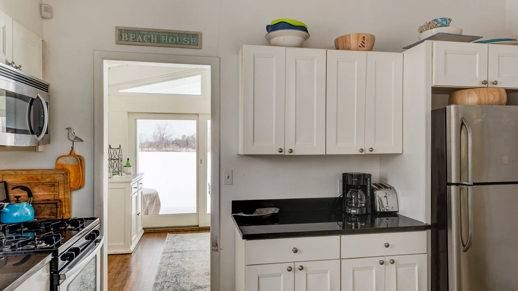 A kitchen with white cabinets, dark countertops, and stainless steel appliances.