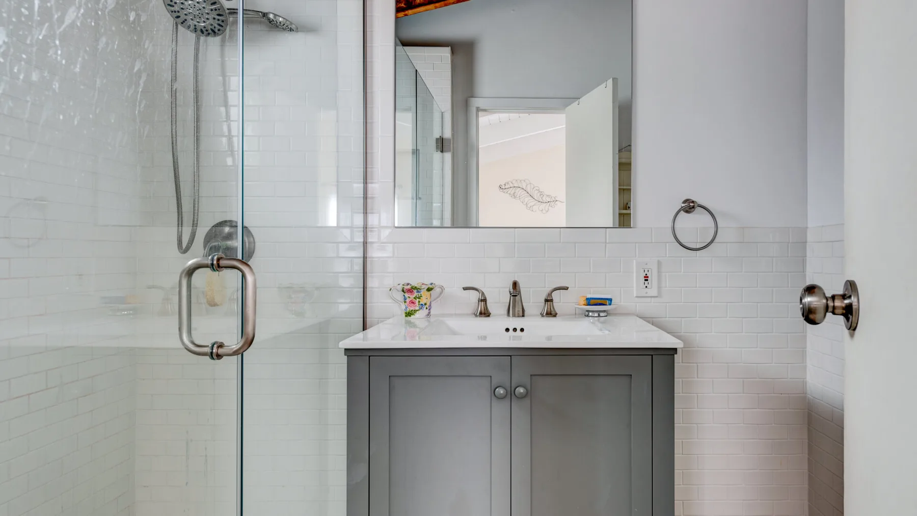 A bright bathroom with a glass shower and a vanity beneath a mirror.