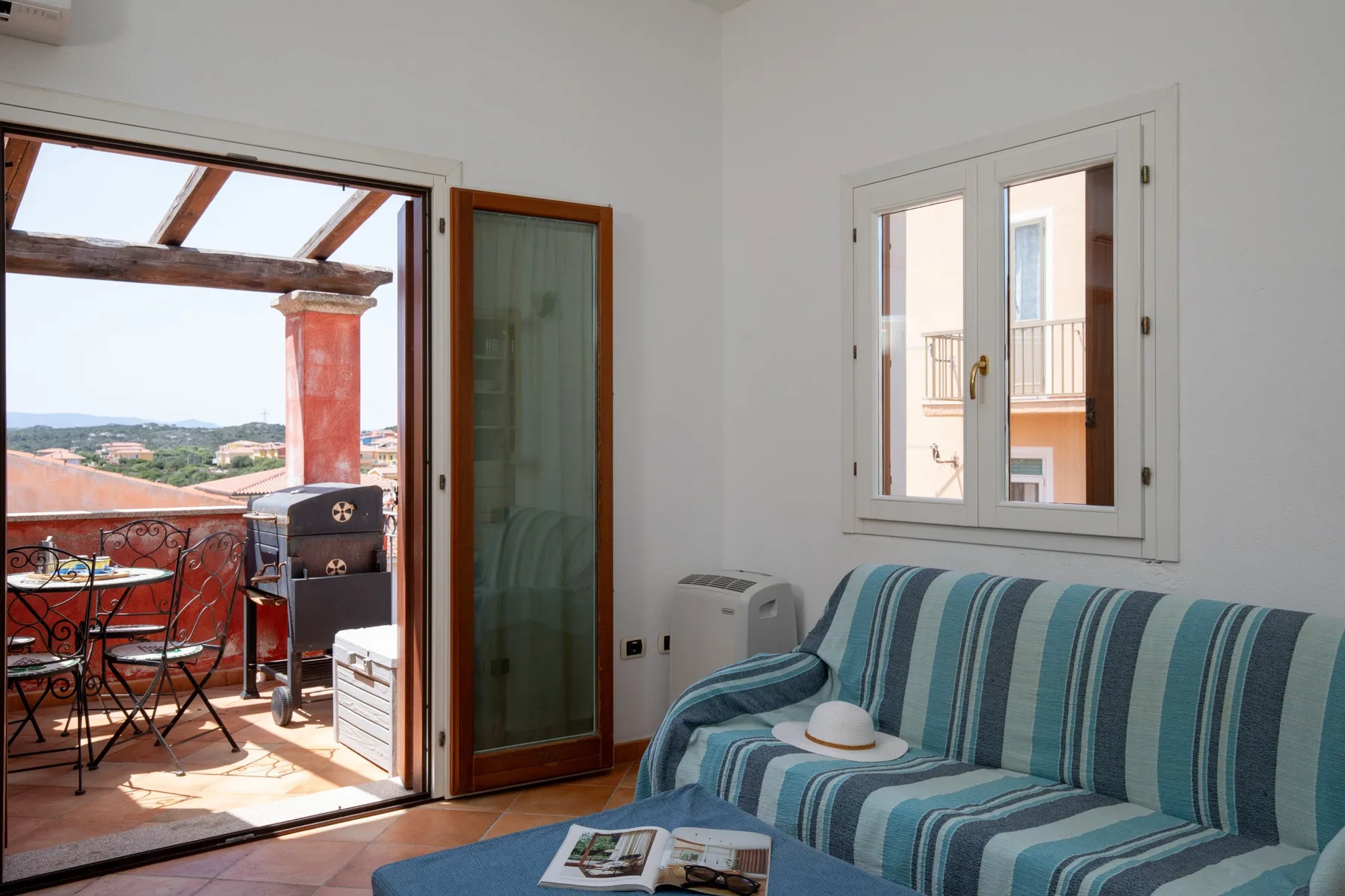 A living room with striped seating beside an open balcony doorway.