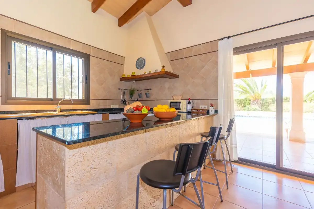 A kitchen with a stone counter, bar seating, and sliding glass doors.