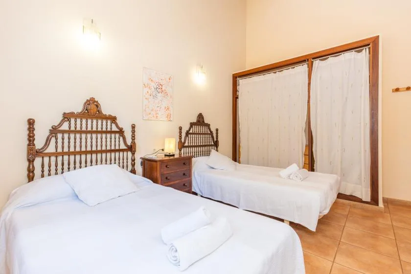A bedroom with two beds and a wooden bedside table.