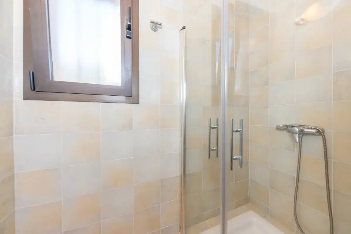 A tiled bathroom with a shower and a frosted window.