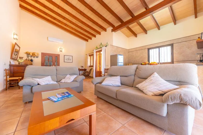 A living room with seating, a low table, and exposed wooden ceiling beams.