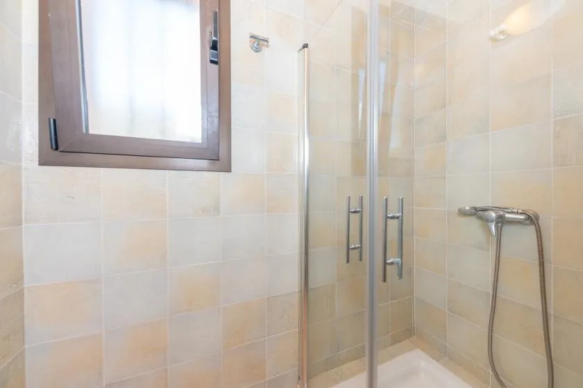 A tiled bathroom with a glass shower and a frosted window.