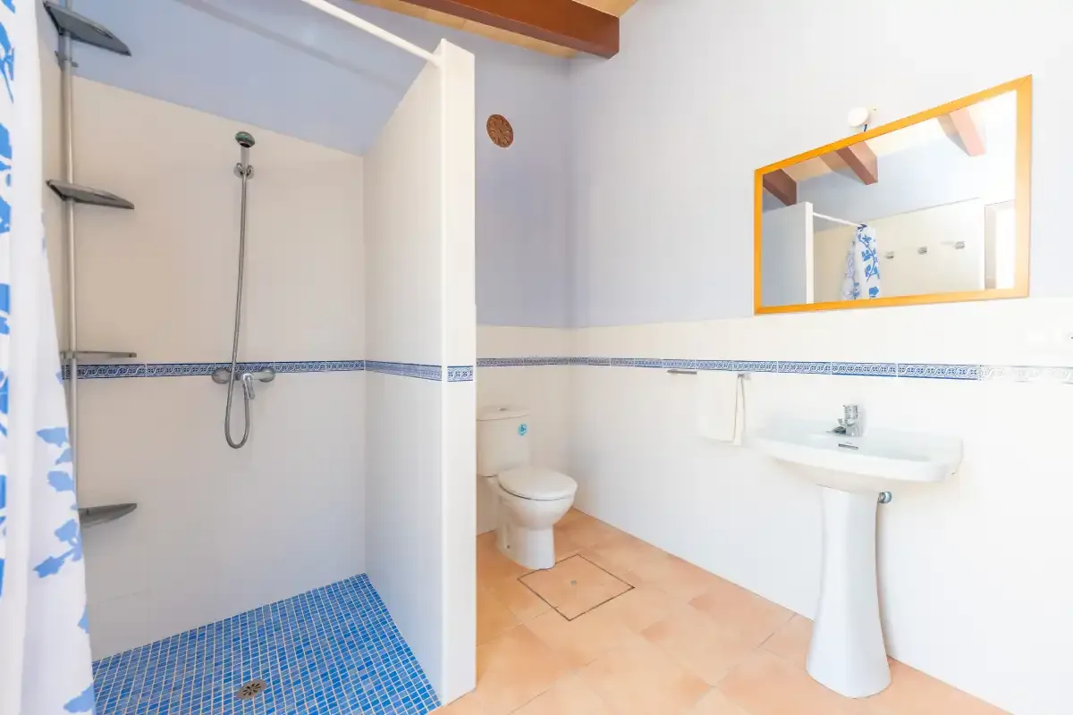 A bathroom with a shower, toilet, and pedestal sink.