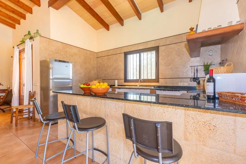 A kitchen with a long counter, bar seating, and a window.
