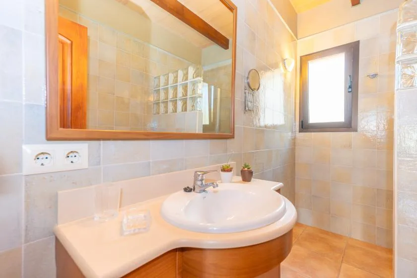 A tiled bathroom with a curved vanity, sink, and wall mirror.