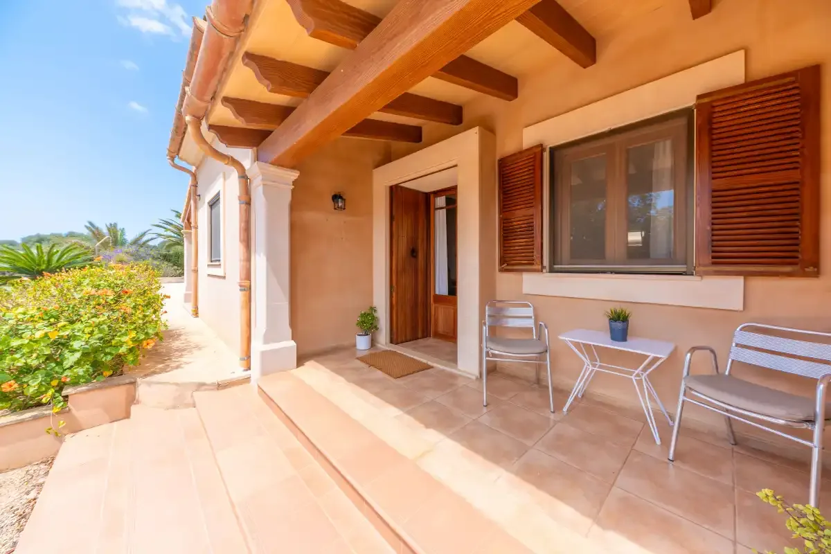 A covered patio with a doorway, window, and outdoor seating.